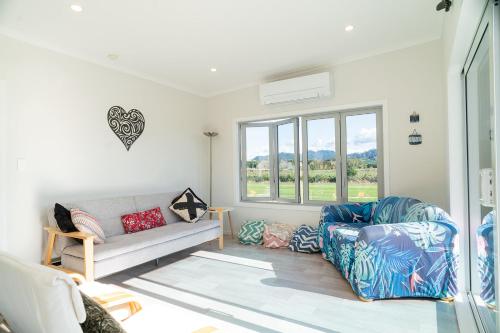 a living room with a couch and a chair at Reel retreat - sunny with views! in Waihi Beach