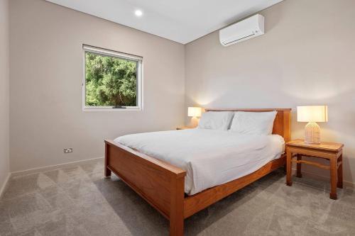 a bedroom with a bed with two lamps and a window at Bayscape - Modern Beachside Retreat with Ocean View in Dunsborough
