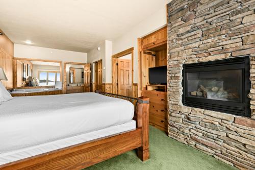 a bedroom with a bed and a stone fireplace at Amazing Superior Lake View Condo and Heated Pools in Two Harbors
