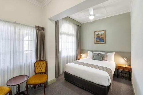 a hotel room with a bed and a chair at George Inn Rooms at Royal Tenterfield in Tenterfield
