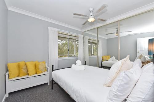 una camera da letto con un letto bianco e uno specchio di Windella Cottage a North Rothbury