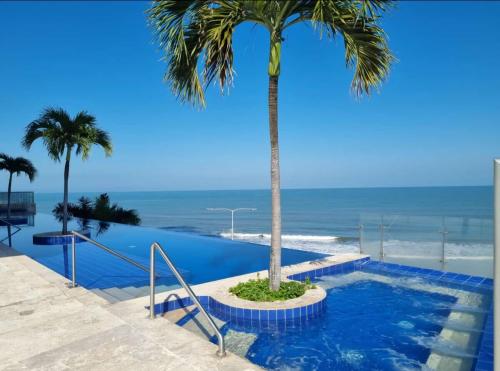a palm tree in a pool with the ocean in the background at Ikigai frente al mar con piscina infinita y Gym in Cartagena de Indias