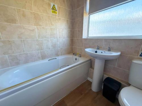 ein Badezimmer mit Badewanne und Waschbecken in der Unterkunft Dog Friendly Chalet With Outdoor Seating At Broadland Park And Marina Ref 12050B in Lowestoft