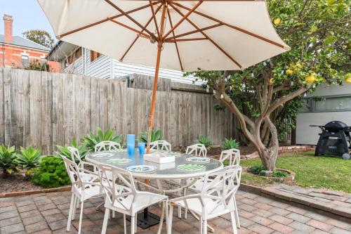 a table and chairs with an umbrella on a patio at Mrs Issy in Queenscliff