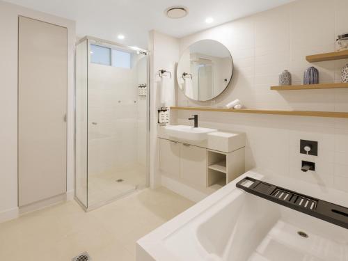a white bathroom with a shower and a sink at The Sebel Palm Cove in Palm Cove