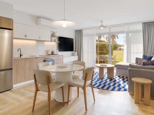 a kitchen and living room with a table and chairs at The Sebel Palm Cove in Palm Cove