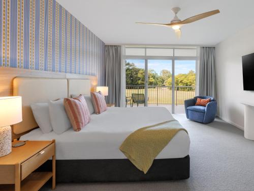 a bedroom with a large bed and a tv at The Sebel Palm Cove in Palm Cove