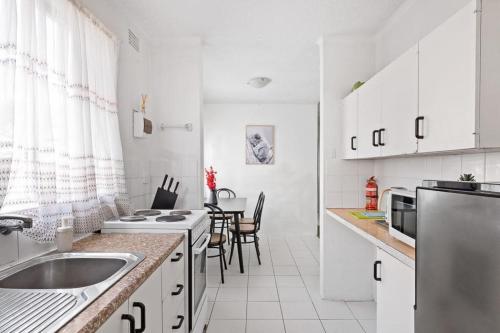 a white kitchen with a sink and a refrigerator at Modern Private Single Room - Centrally Located at Liverpool - Shared Bathroom in Liverpool