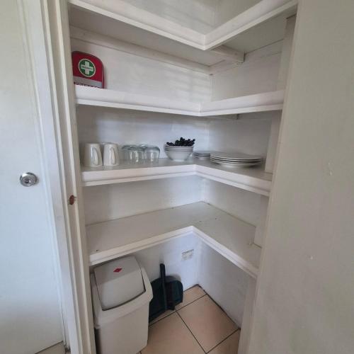 a small white pantry with a toilet in it at Breezy Retreats A Cosy Getaway in Kingston