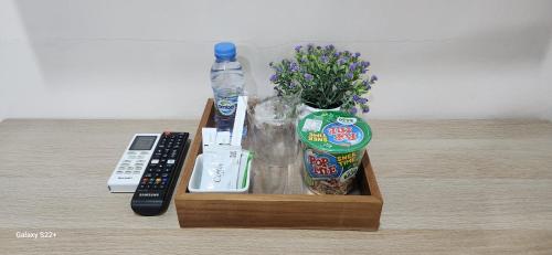 a wooden tray with a remote control and a bottle of water at Elbara Guest House Syariah in Banjarbaru