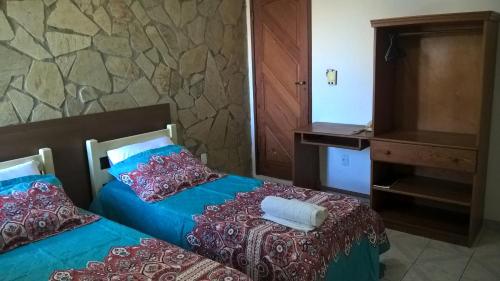 two beds in a room with a stone wall at Pousada Porto Villas in Lauro de Freitas