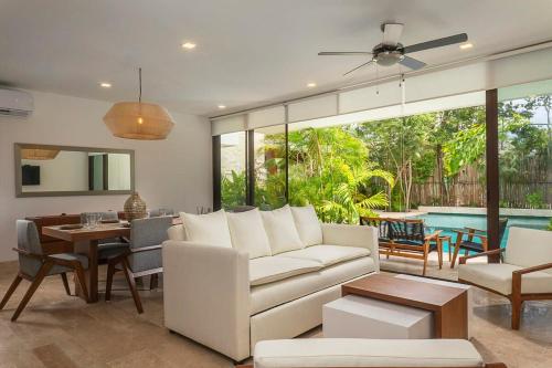 a living room with a white couch and a pool at Relaxing 2BR Condo Omara with Direct Pool Access in Tulum