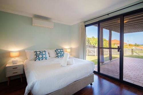 a bedroom with a bed and a sliding glass door at Bondys Beach House - Panoramic Beachside Living in Prevelly