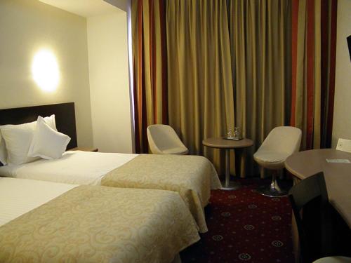 a hotel room with two beds and a table and chairs at Hotel Berthelot in Bucharest
