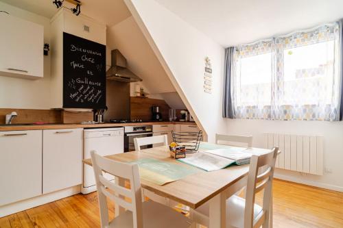 a kitchen with a wooden table and a kitchen with white cabinets at Bienvenue chez Marie et Guillaume in Carentan