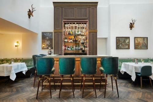a restaurant with green chairs and a bar at Hotel Goldener Hirsch, A Luxury Collection Hotel, Salzburg in Salzburg