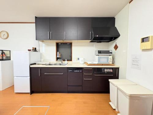 a kitchen with black cabinets and a white refrigerator at 夏様香驛 Historic Kyoto Villa, 4LDK Private House, Perfect for Families in Kyoto