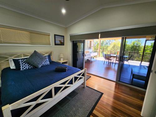 a bedroom with a large bed and a balcony at Avoca Holiday House K'Gari in Kingfisher Bay