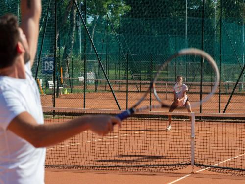 two people playing tennis on a tennis court at Apartment in Albarella near Beach & Activities in Palazzo Vianello