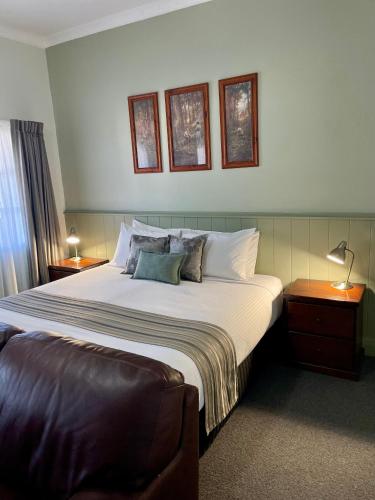 a bedroom with a large bed with two tables and a lamp at George Inn Rooms at Royal Tenterfield in Tenterfield
