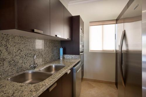 a kitchen with a sink and a stainless steel refrigerator at Condo Maravilla - New luxurious condo 300mt from the beach in Cabo San Lucas
