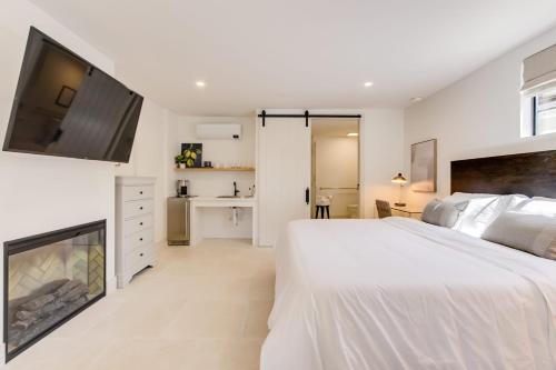 a white bedroom with a large bed and a flat screen tv at Casa Valerio - Boutique Suites in Downtown Santa Barbara in Santa Barbara