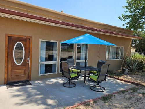 a table with chairs and a blue umbrella in front of a house at Casita La Mesilla in Espanola