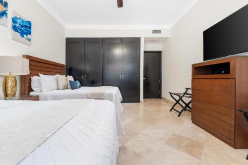 a bedroom with two beds and a flat screen tv at Condo Maravilla - New luxurious condo 300mt from the beach in Cabo San Lucas