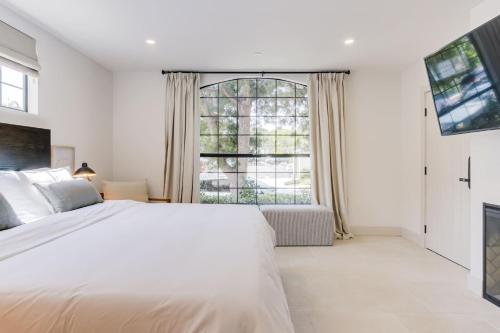 a bedroom with a white bed and a large window at Casa Valerio - Boutique Suites in Downtown Santa Barbara in Santa Barbara