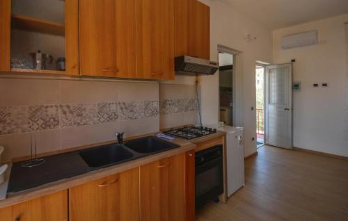 a kitchen with wooden cabinets and a sink and a stove at Beautiful Home In Marzamemi in Marzamemi