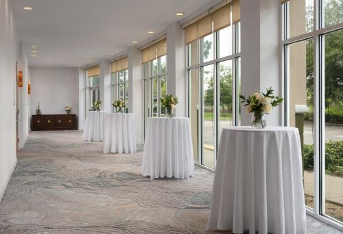 a row of tables with flowers on them in a room with windows at Holiday Inn Jacksonville E 295 Baymeadows by IHG in Jacksonville