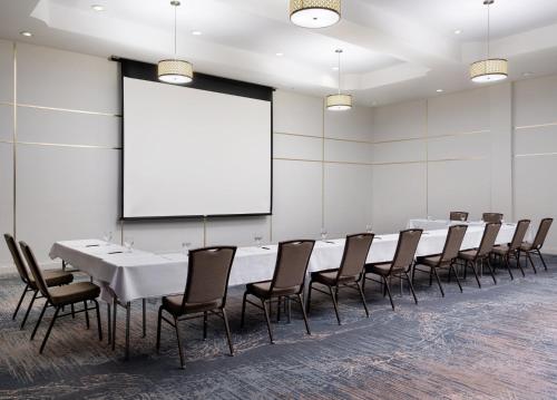 a conference room with a long table and chairs and a screen at Holiday Inn Jacksonville E 295 Baymeadows by IHG in Jacksonville