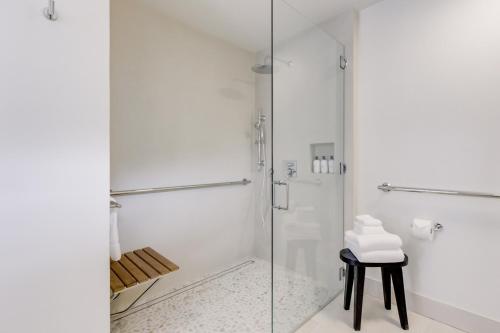 a bathroom with a glass shower and a stool at Casa Valerio - Boutique Suites in Downtown Santa Barbara in Santa Barbara