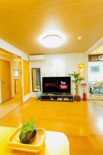a living room with a tv and a table at 晶 距离车站步行5分钟 关西机场难波心斋桥直达 5 bedroom最多可住13人 超大客厅大电视有Netflix in Osaka
