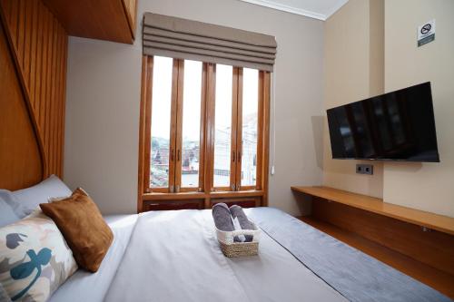 a bedroom with a bed with a flat screen tv at Casa de Java Jogja in Kejayan