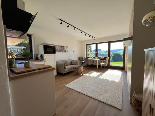 a living room with a kitchen and a living room with a table at Neu - Ferienwohnung Allgäuparadies - Traumhafte Aussichten mitten in der Natur des Westallgäus in Oberreute