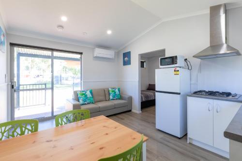 a kitchen and living room with a refrigerator and a table at Kalbarri Tudor Holiday Park in Kalbarri