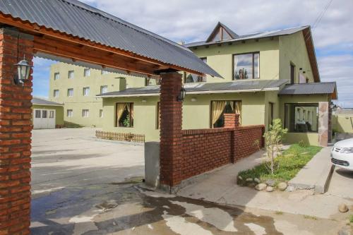 a house with a brick wall next to a parking lot at El Alamo Hotel in Comandante Luis Piedra Buena
