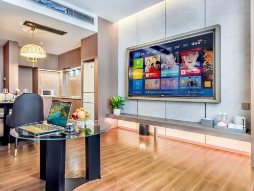 a living room with a tv and a laptop on a table at Yashihui Hotel in Qumul