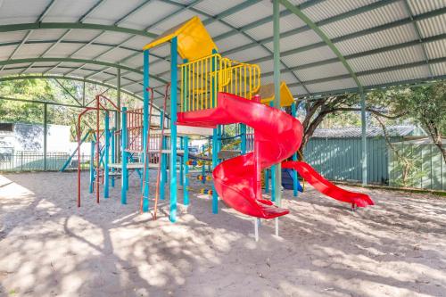a playground with a red and blue slide at Rockingham Holiday Village in Rockingham