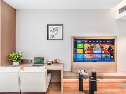 a living room with a flat screen tv on a wall at Yashihui Hotel in Qumul