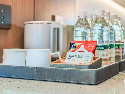 a tray with cups and bottles of water on a counter at Yashihui Hotel in Qumul