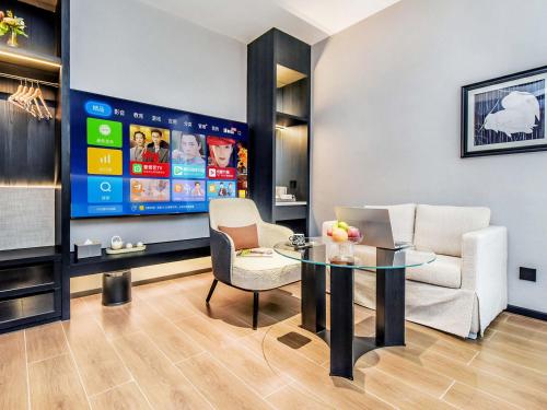 a living room with a table and chairs and a tv at Yashihui Hotel in Qumul