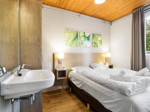 a bathroom with a sink and a bed in a room at Bungalow in Putten near Veluwe Forest in Putten