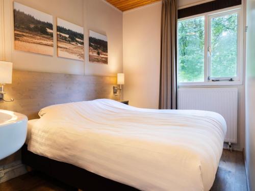a bedroom with a bed and a sink and a window at Cozy Forest Retreat Near Putten in Putten