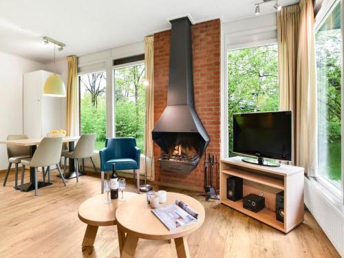 a living room with a fireplace and a tv at Cozy Forest Retreat Near Putten in Putten