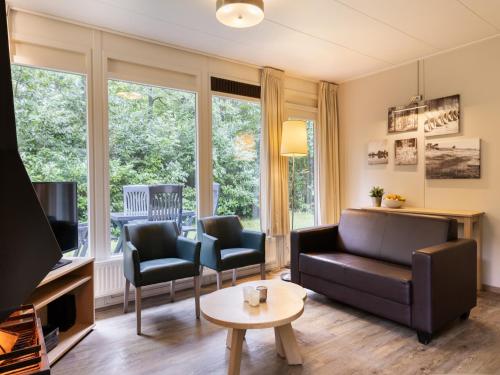 a living room with a couch and chairs and a tv at Cozy Forest Retreat Near Putten in Putten