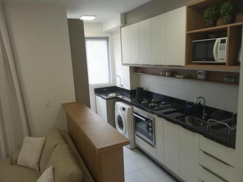 a kitchen with a stove top oven next to a couch at Apto Clássico - luxo perto da WEG in Jaraguá do Sul
