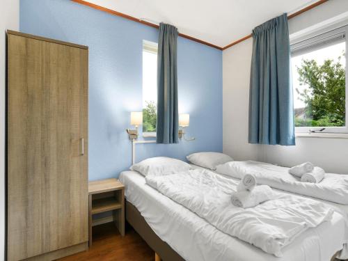 two beds in a room with blue walls and windows at Holiday Home in Brouwershaven by Grevelingenmeer in Brouwershaven