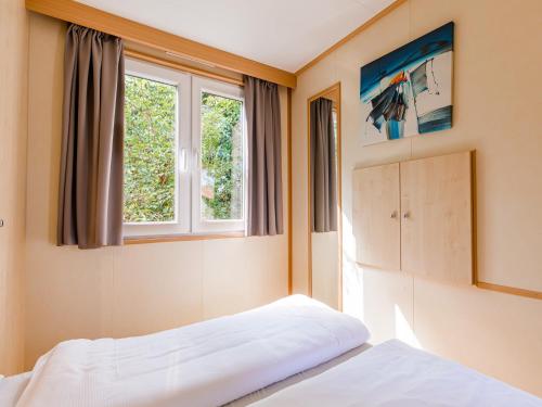 a bedroom with two beds and two windows at Chalet by the Water in Leukermeer in Well